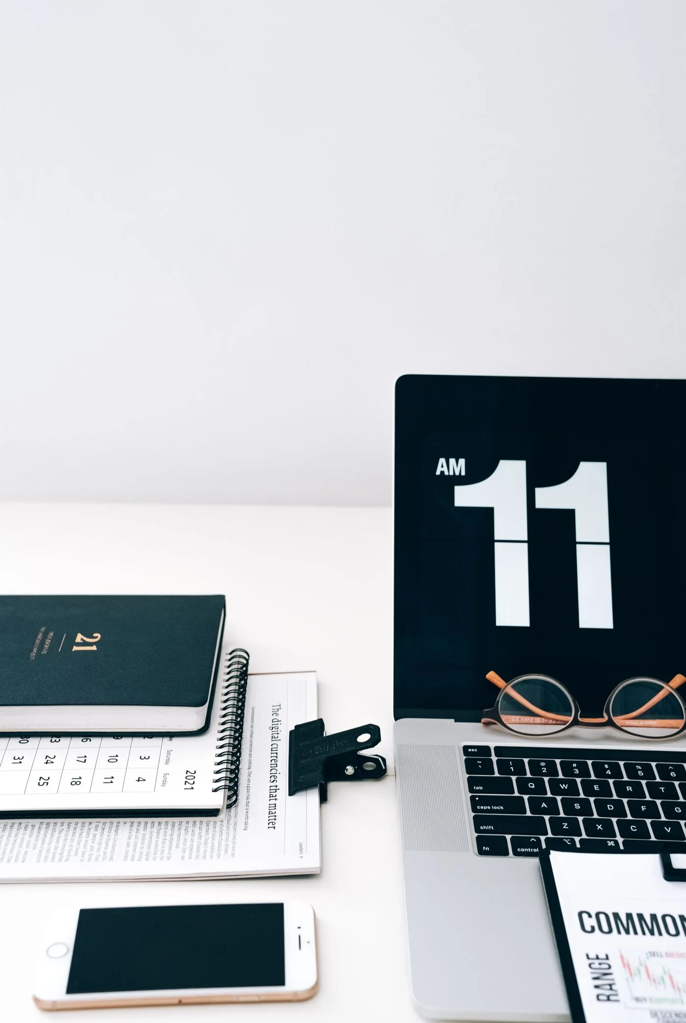 Kalender und Digitaluhr neben einem Laptop