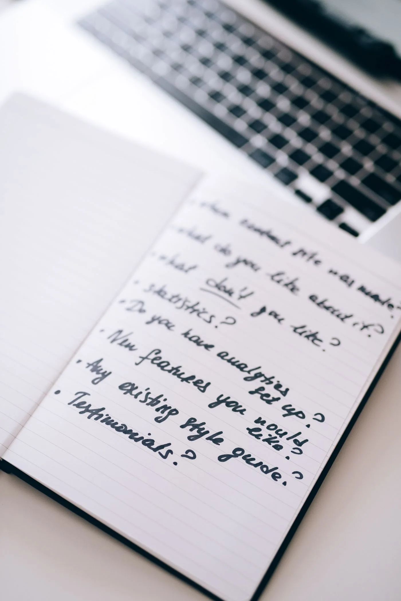 Handschriftliche Geschäftsnotizen neben einem Laptop
